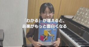 ピアノの前でセオリーのテキストを持つ生徒