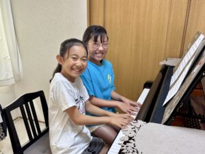 同じ学年の生徒2人が笑顔でピアノ連弾を楽しむ様子